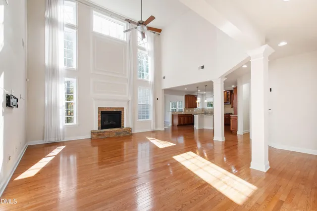 a view of a livingroom with wooden floor a fireplace and windows