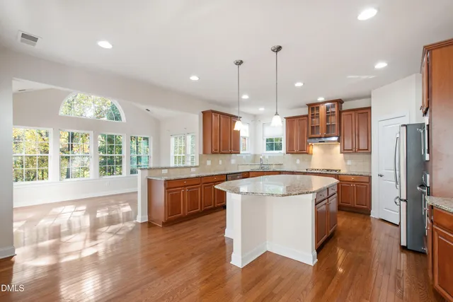 a large kitchen with stainless steel appliances kitchen island a large counter top and a wooden floors