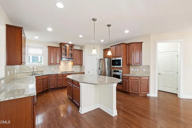 a kitchen with stainless steel appliances granite countertop wooden floors and white cabinets