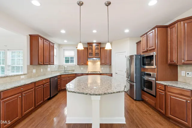 a kitchen with stainless steel appliances granite countertop a refrigerator a sink and a stove