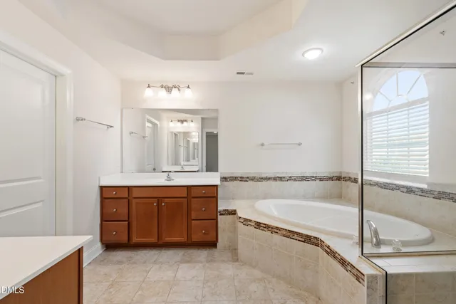 a spacious bathroom with a tub sink and mirror