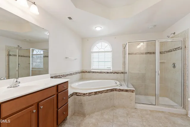 a bathroom with a tub sink shower and mirror