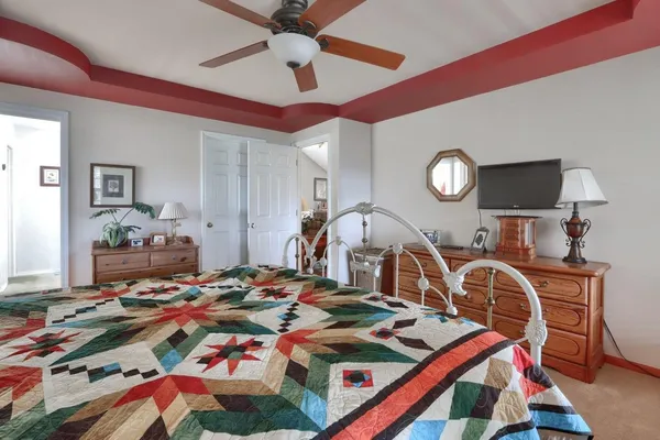 a bed room with a bed a dresser and potted plants