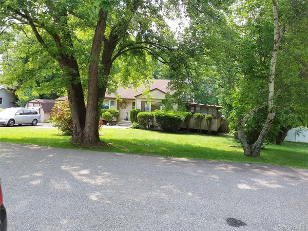 a view of a house with a big yard and large trees