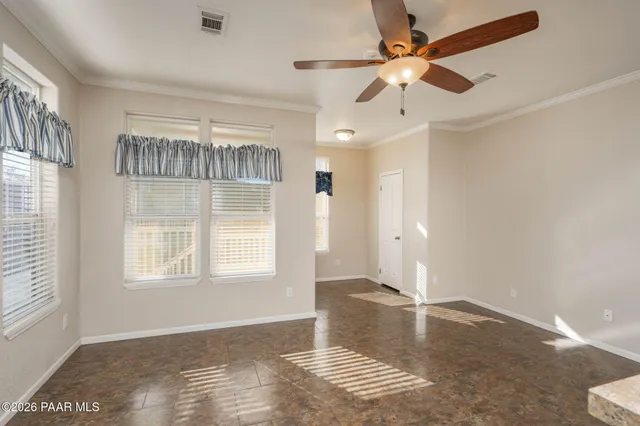 a view of an empty room with window and chandelier fan