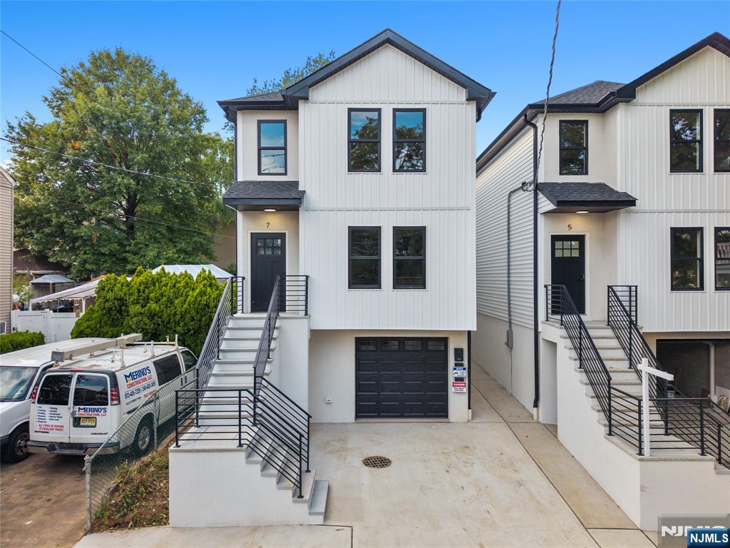 a view of a white house with large windows and couches chairs