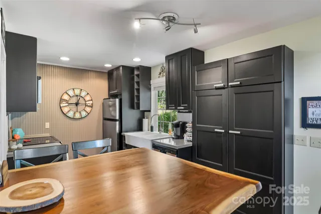a living room with stainless steel appliances furniture a rug and a kitchen view