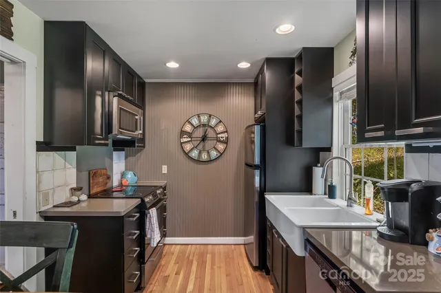 a kitchen with stainless steel appliances granite countertop a refrigerator a stove and a sink with wooden cabinets