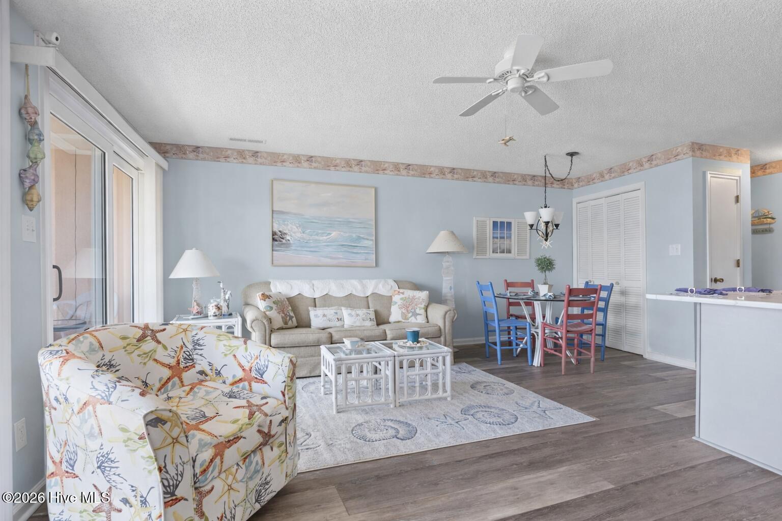 9201 Coast Guard Road, Unit I207 Emerald Isle, NC 28594 - Photo 26 of 26 Living room with open floor plan, coastal décor, and direct balcony access through sliding glass doors. Bright interior creates an inviting gathering space.
