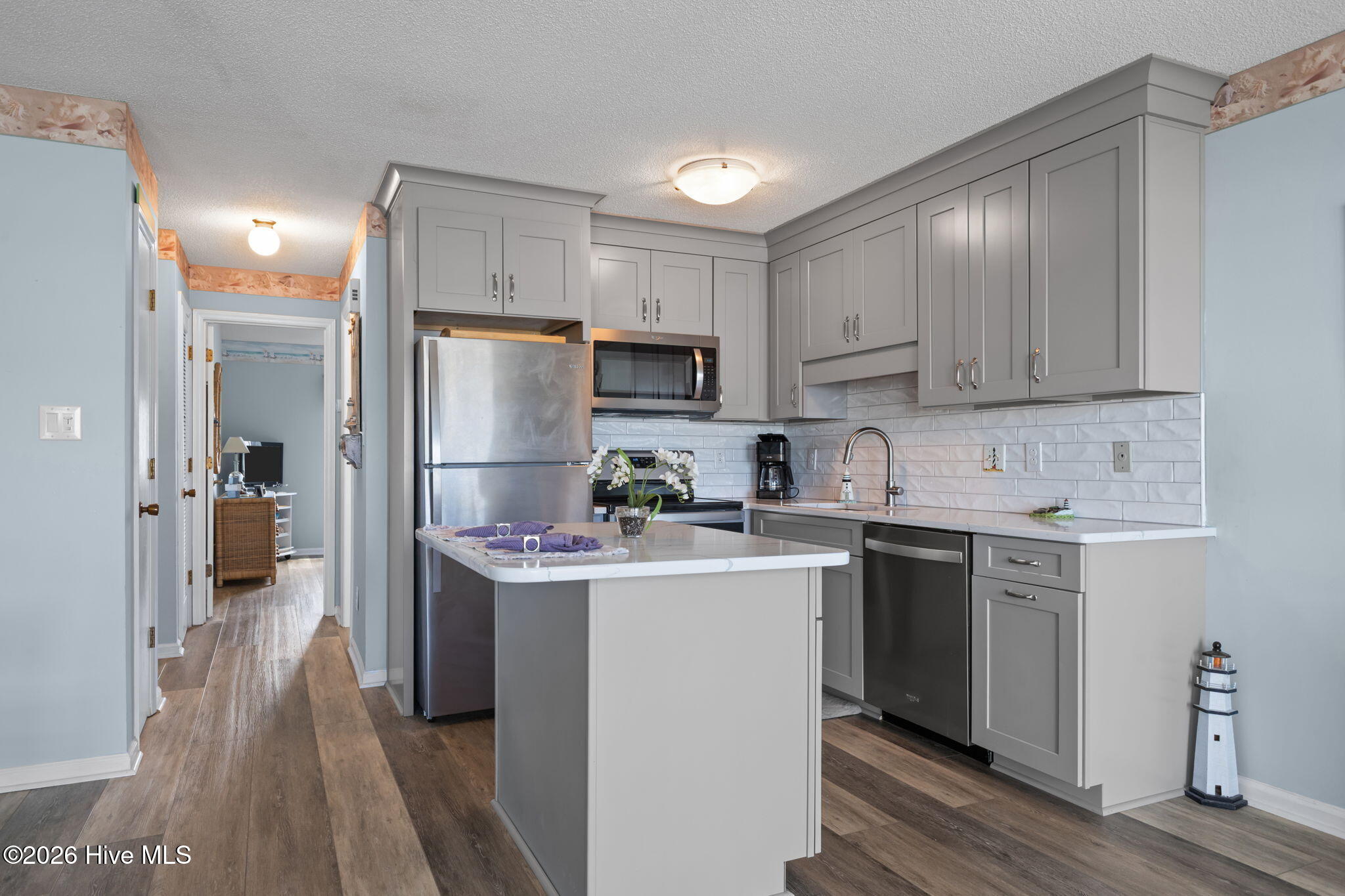 9201 Coast Guard Road, Unit I207 Emerald Isle, NC 28594 - Photo 6 of 26 Kitchen featuring shaker-style cabinetry, stainless steel appliances, subway tile backsplash, and a center island with additional prep space. Open layout connects seamlessly to the main living area.