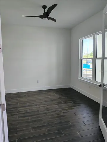 a view of an empty room with wooden floor and a window