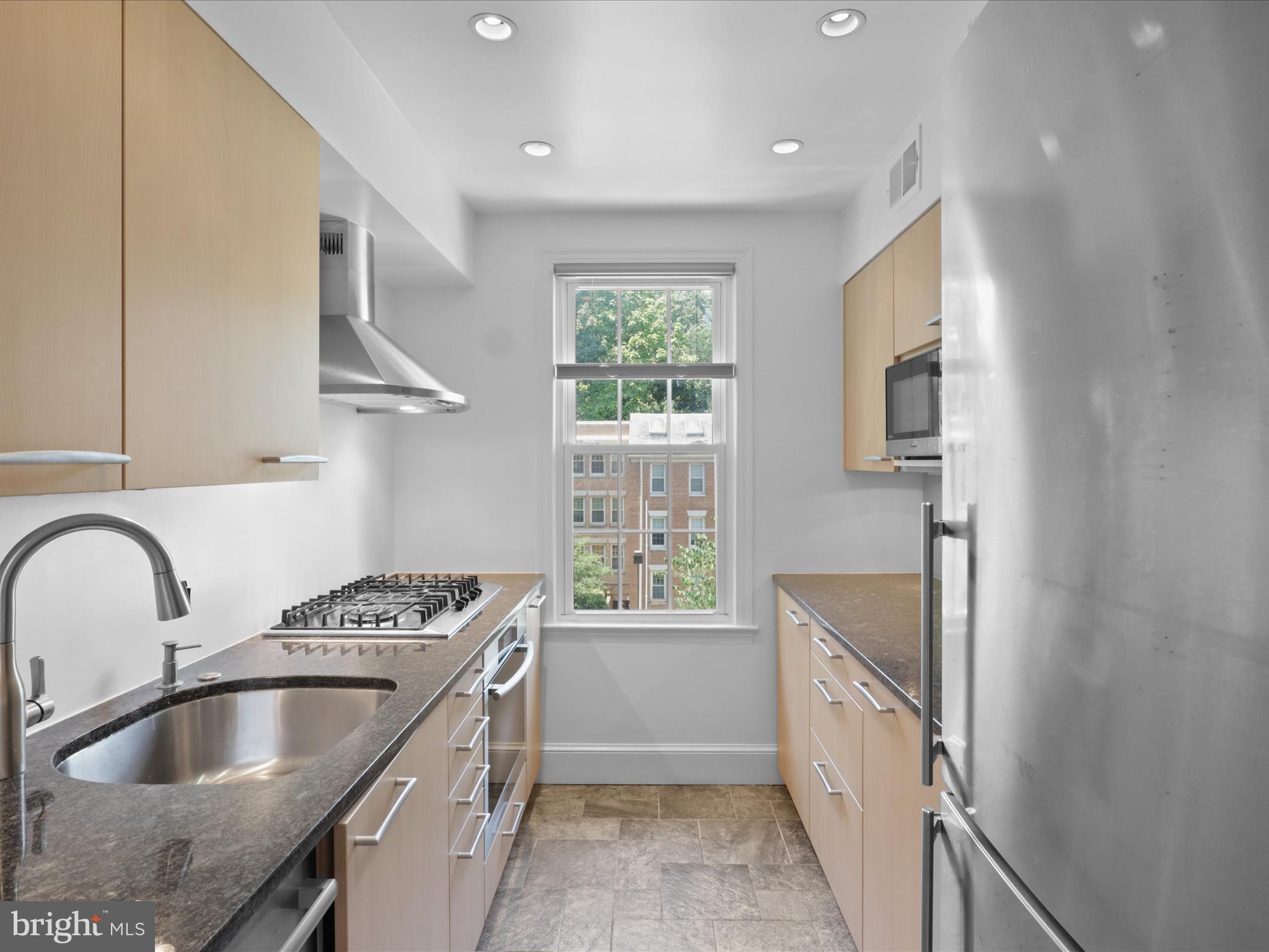 2721 Ordway Street Northwest, Unit 5 Washington, DC 20008 - Photo 15 of 39 a kitchen with kitchen island granite countertop a sink stainless steel appliances and window