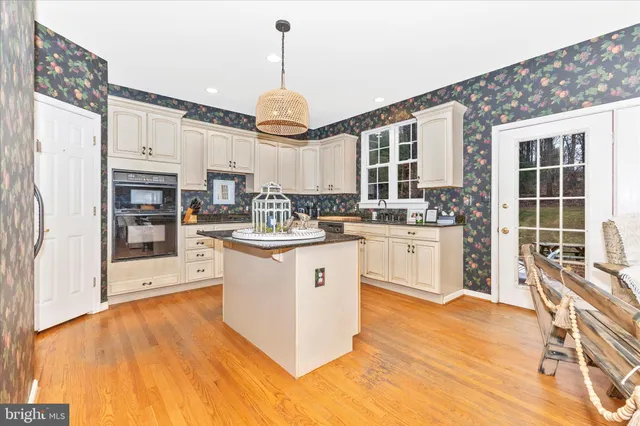 a kitchen with kitchen island granite countertop a sink a counter space cabinets and stainless steel appliances