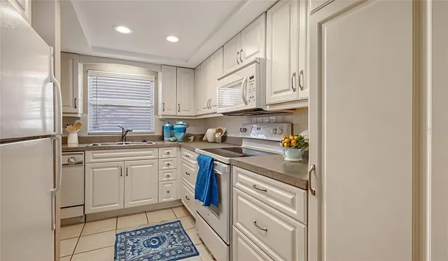a kitchen with granite countertop white cabinets white stainless steel appliances and a sink
