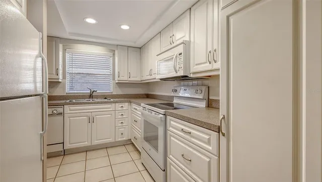 a kitchen with white cabinets and appliances
