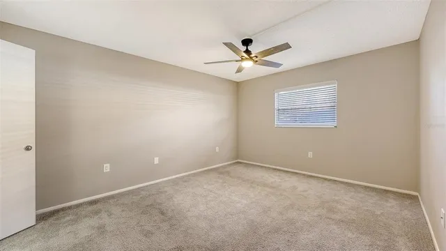 an empty room with a window and ceiling fan