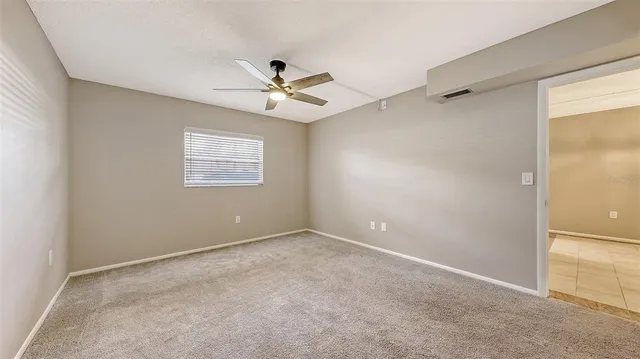 an empty room with a window and a ceiling fan