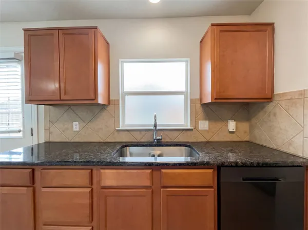 a kitchen with granite countertop wooden cabinets a sink and a window