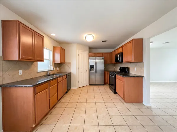 a large kitchen with stainless steel appliances granite countertop a stove a sink dishwasher and a refrigerator