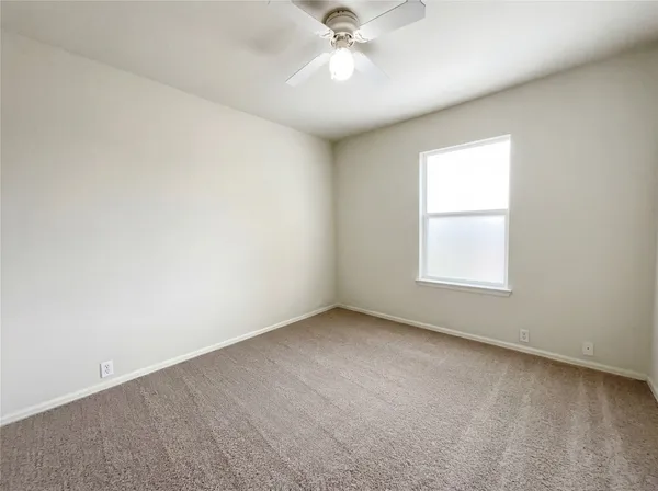 an empty room with a window and a ceiling fan