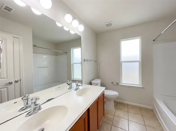 a bathroom with a sink double vanity granite and a toilet