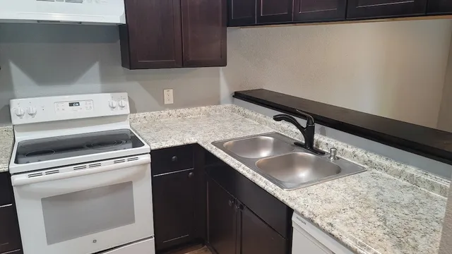 a kitchen with granite countertop a sink stove and cabinets