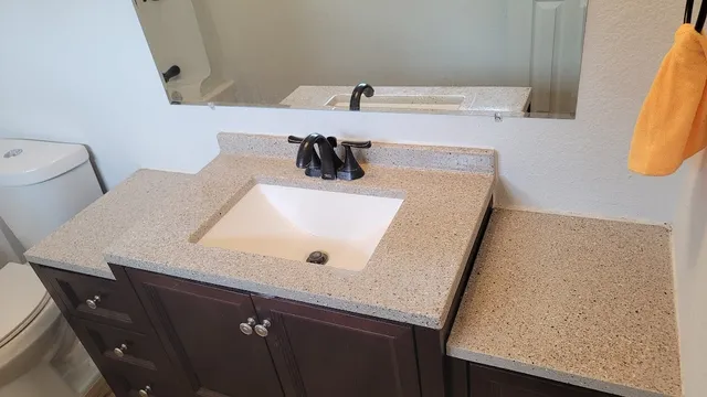a bathroom with a granite countertop sink and a mirror