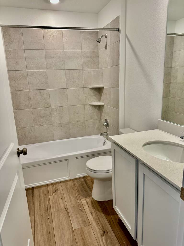 4104 Home Pl Road Georgetown, TX 78628 - Photo 13 of 35 Bathroom with vanity, light wood-type flooring, shower / bath combination, and a textured wall