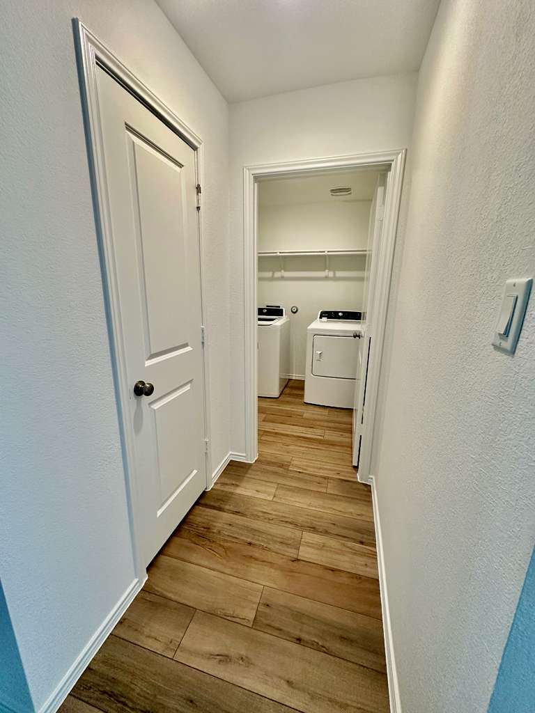 4104 Home Pl Road Georgetown, TX 78628 - Photo 16 of 35 Hallway featuring a textured wall, light wood-style floors, and washing machine and clothes dryer