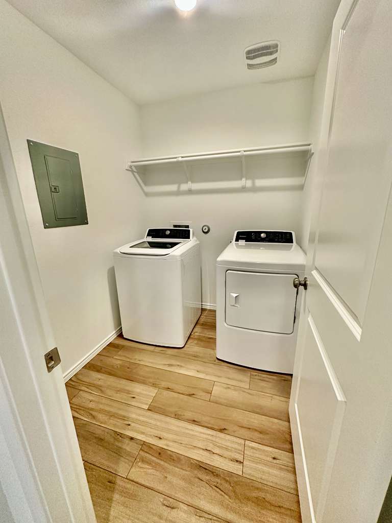 4104 Home Pl Road Georgetown, TX 78628 - Photo 17 of 35 Laundry area featuring light wood-style flooring, electric panel, and washing machine and dryer