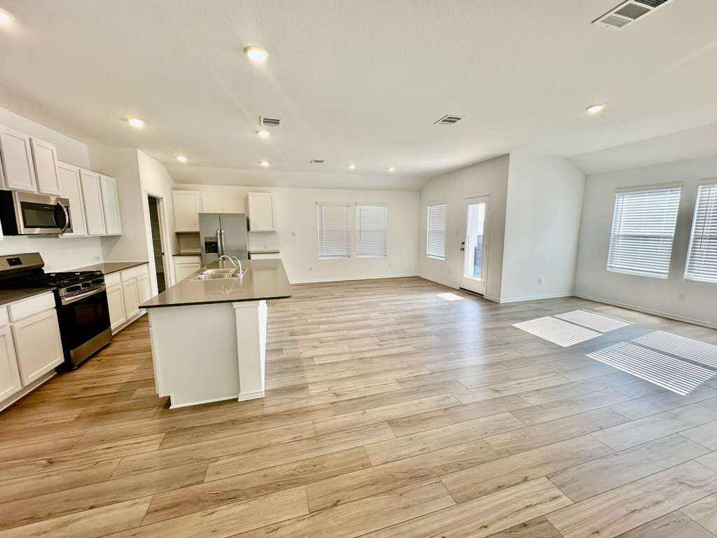 4104 Home Pl Road Georgetown, TX 78628 - Photo 34 of 35 Kitchen with stainless steel appliances, dark countertops, white cabinetry, open floor plan, and an island with sink