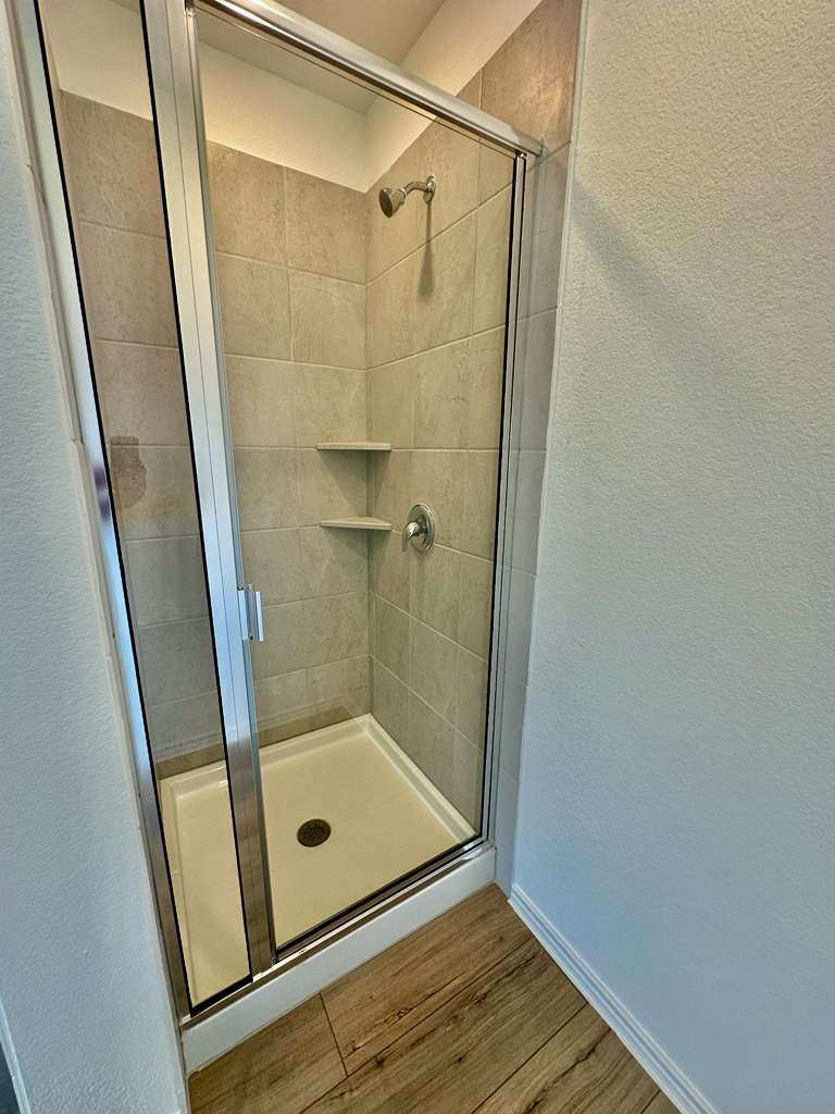 4104 Home Pl Road Georgetown, TX 78628 - Photo 22 of 35 Full bath featuring a textured wall, a shower stall, and wood finished floors