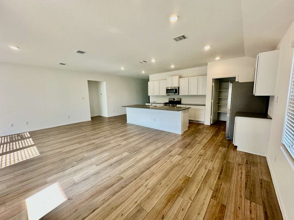 4104 Home Pl Road Georgetown, TX 78628 - Photo 35 of 35 Kitchen featuring white cabinets, dark countertops, open floor plan, a center island with sink, and light wood-type flooring
