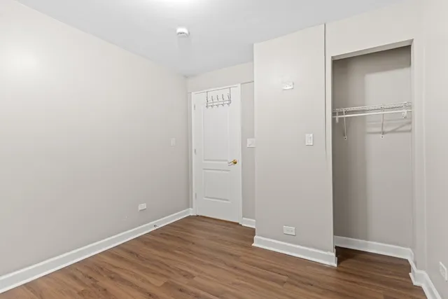 a view of an empty room with wooden floor and closet