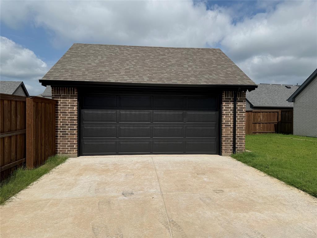 1840 Rosedale Avenue Van Alstyne, TX 75495 - Photo 22 of 24 Detached garage featuring a dark panel-style door, brick siding, and a gabled shingle roof
