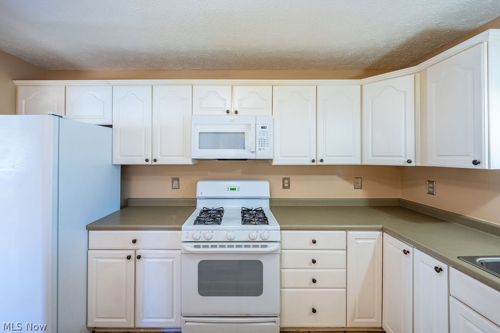 3601 River Road Vienna, WV 26105 - Photo 12 of 40 Kitchen featuring white appliances, white cabinets, a textured ceiling, and light countertops
