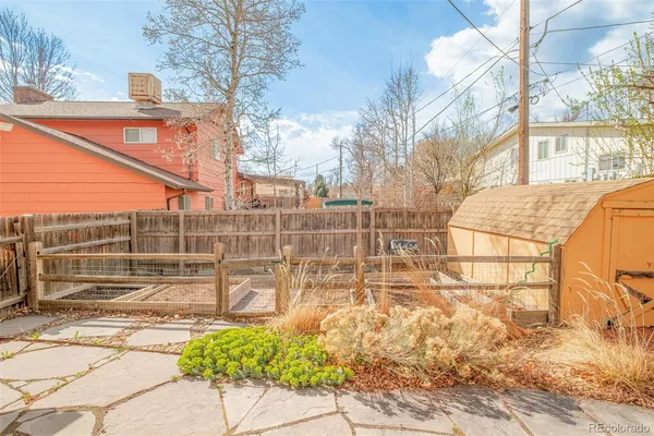 a backyard of a house with table and chairs under an umbrella
