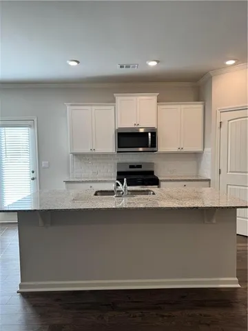a kitchen with granite countertop a sink cabinets and stainless steel appliances