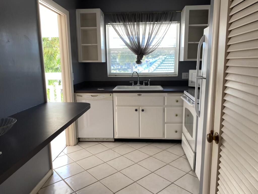 91 Willow Road, Unit 203 Tequesta, FL 33469 - Photo 4 of 9 a kitchen with granite countertop a sink a window and a granite counter top