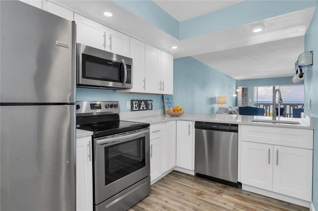 403 Gulf Way, Unit 302 St. Pete Beach, FL 33706 - Photo 7 of 30 a kitchen with stainless steel appliances a stove microwave and sink