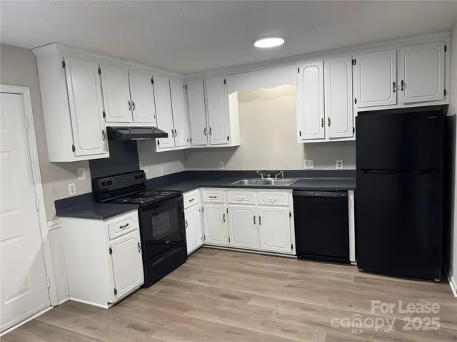 a kitchen with granite countertop white cabinets and black appliances