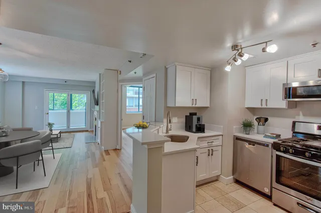 a kitchen with stove a sink dishwasher a dining table and chairs with wooden floor