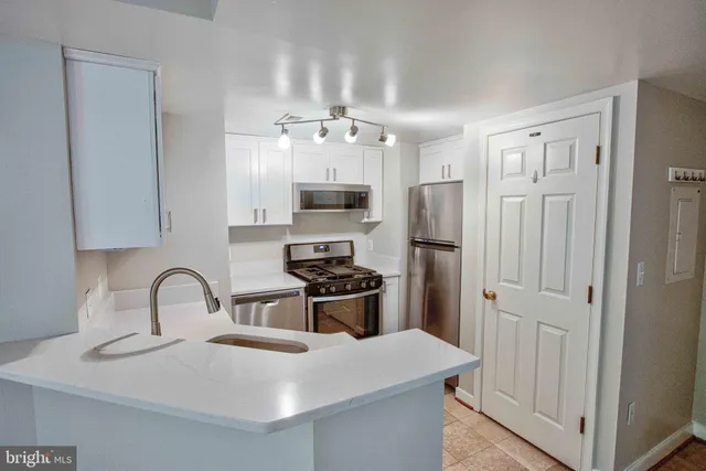 a kitchen with stainless steel appliances granite countertop a sink a stove and refrigerator