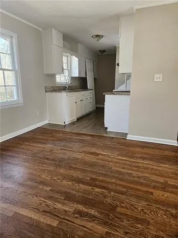 a view of kitchen and empty room with wooden floor