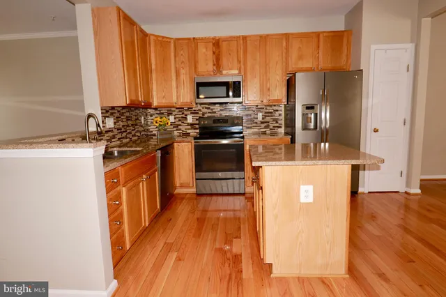 a kitchen with stainless steel appliances granite countertop a refrigerator a stove top oven a sink and dishwasher