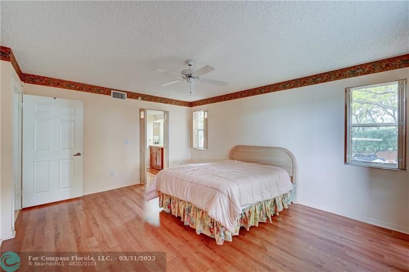 9599 Weldon Circle, Unit A101 Tamarac, FL 33321 - Photo 20 of 28 a bedroom with a bed and wooden floor