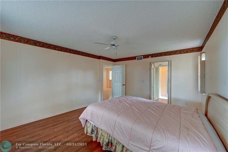 9599 Weldon Circle, Unit A101 Tamarac, FL 33321 - Photo 21 of 28 a bedroom with a bed and wooden floor