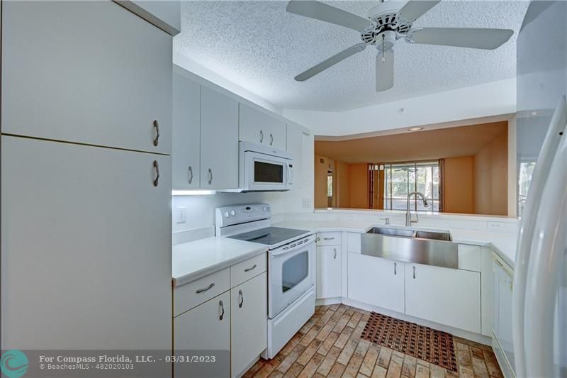 9599 Weldon Circle, Unit A101 Tamarac, FL 33321 - Photo 4 of 28 a kitchen with stainless steel appliances a sink cabinets and a window