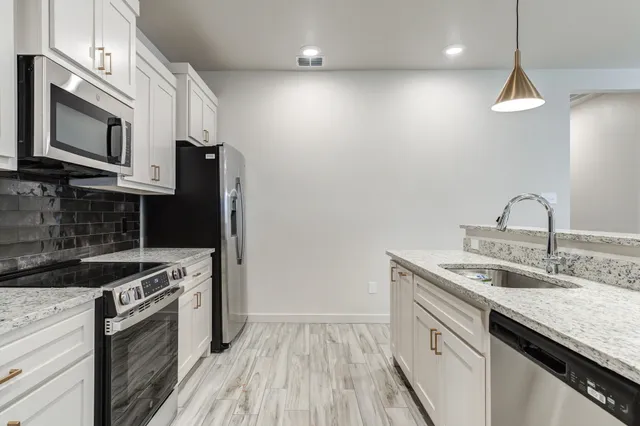 a kitchen with stainless steel appliances granite countertop a sink a stove and a refrigerator