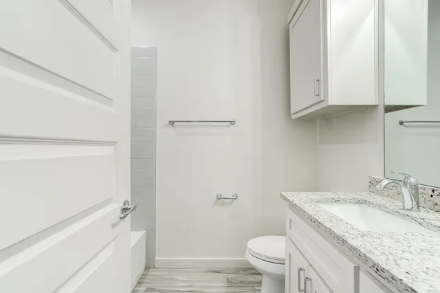 a bathroom with a granite countertop sink a toilet and bathtub